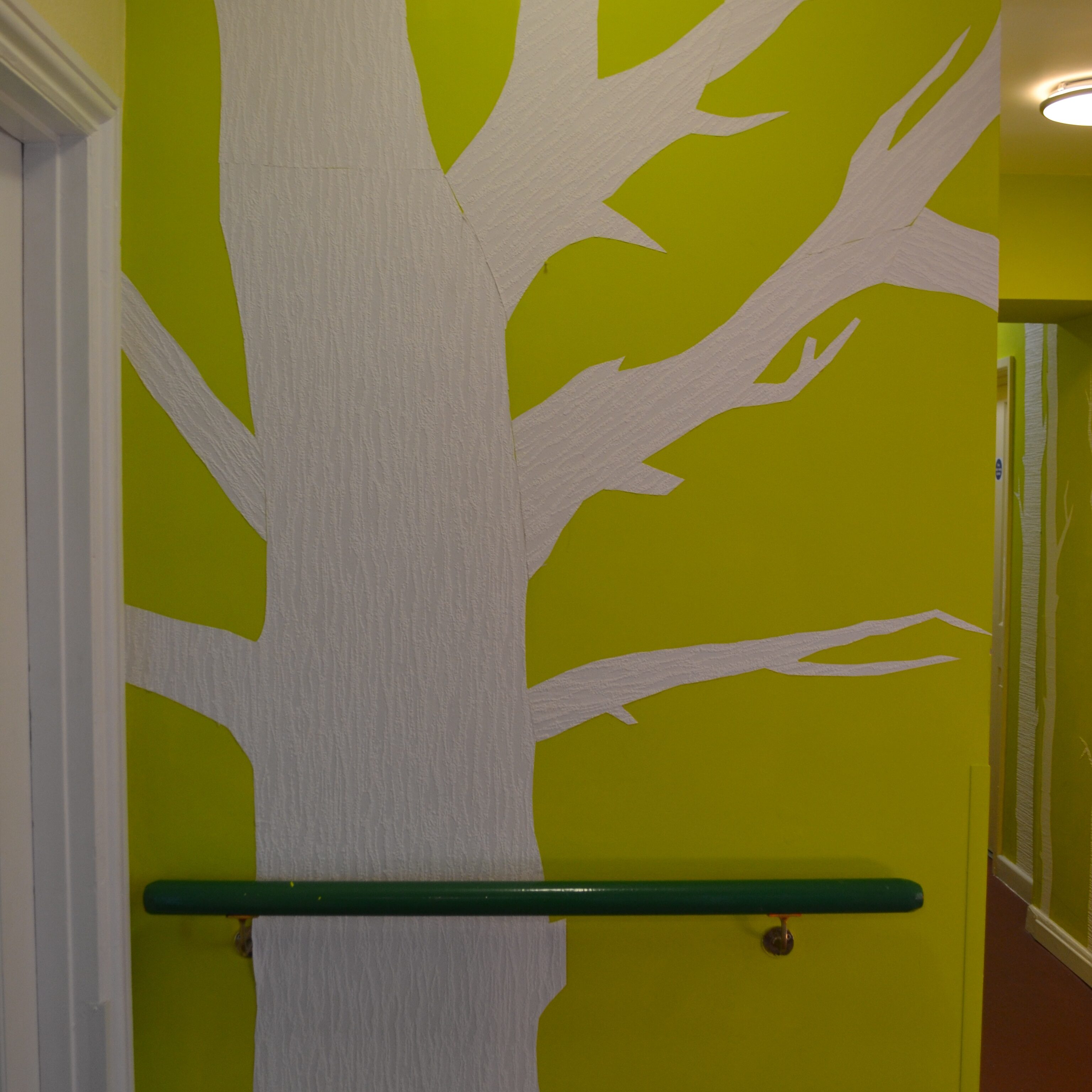 Shows green painted background with paper tree in white.