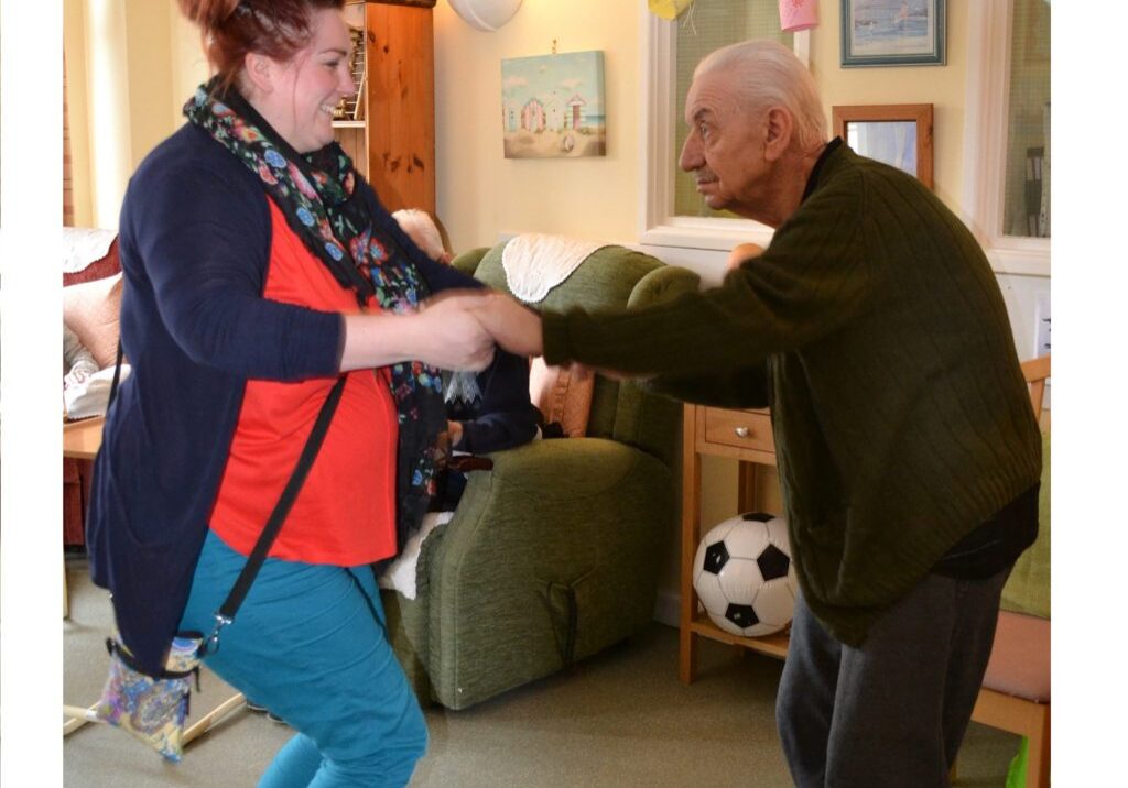 Picture shows male resident dancing and holding hands with a member of activities team.